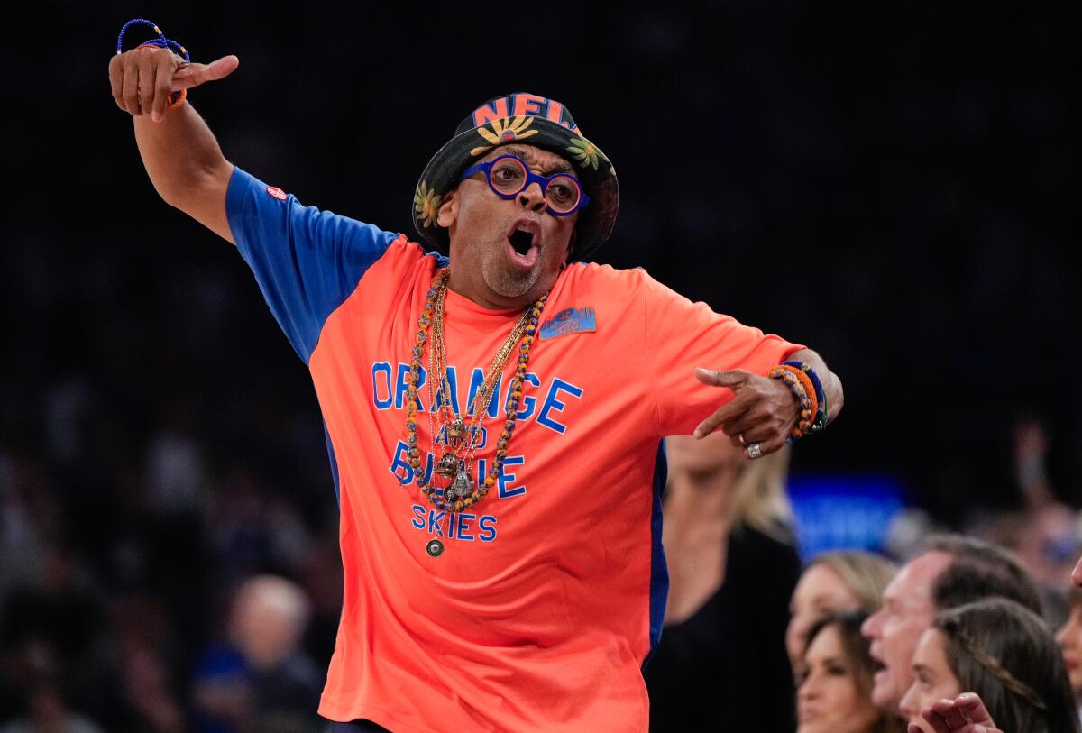 Spike Lee courtside at Madison Square Garden in an orange Knicks Orange and Blue Skies shirt celebrating the Knicks championship run